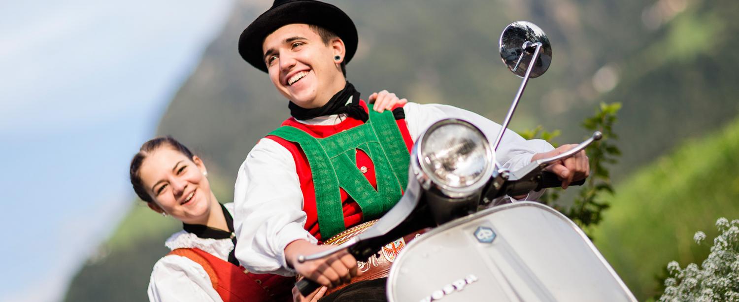 Riding Vespa scooters in South Tyrolean folk costumes